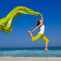 Frau am Strand mit freudigem Luftsprung. Voller Lebensfreude.